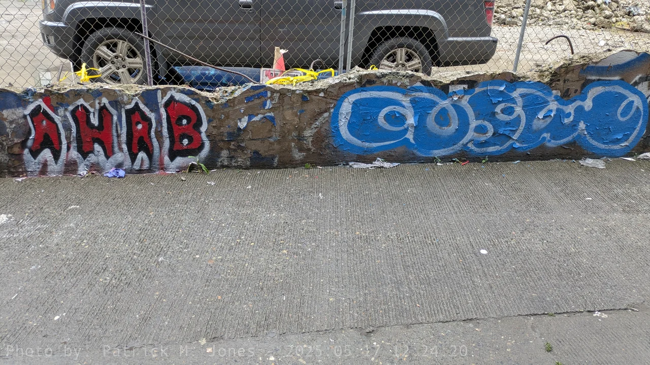 AHAB X COSMO graffiti on a cement wall with metal fence